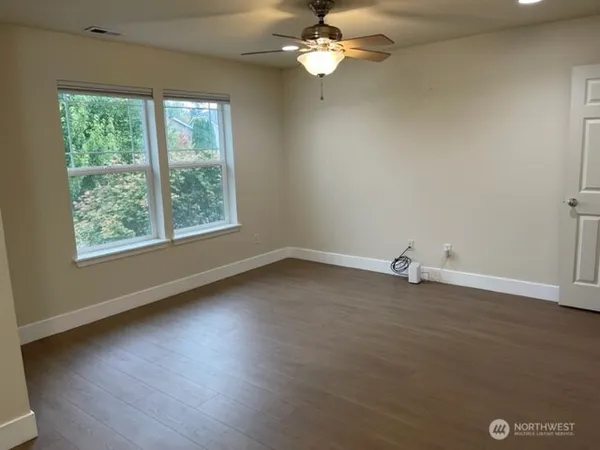 an empty room with wooden floor and windows
