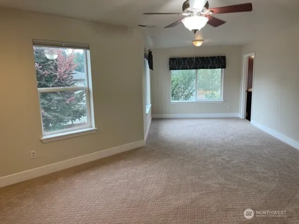 a view of a livingroom with a large window a ceiling fan and chandelier fan