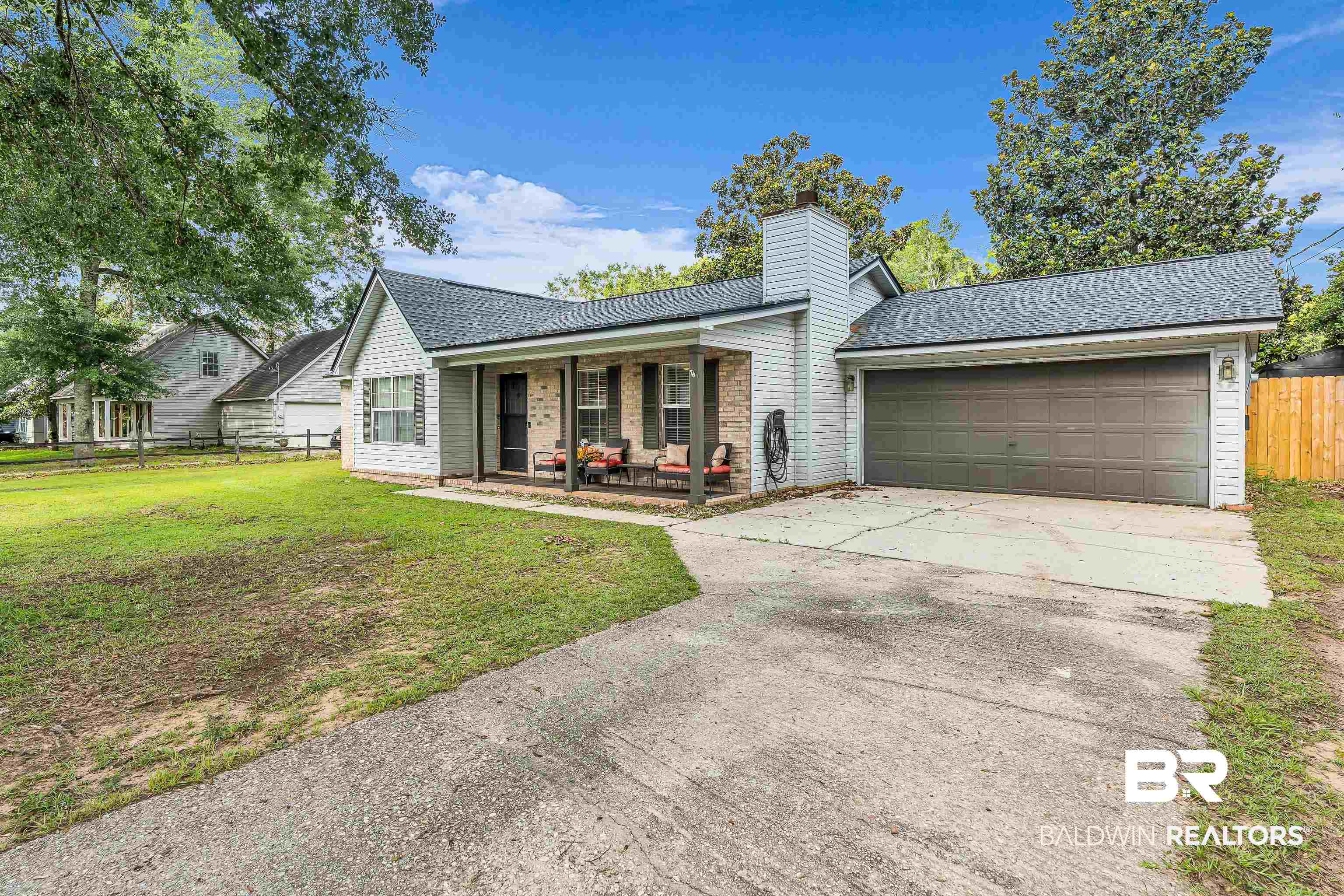 View of front of house with a porch, a garage, concrete driveway, a shingled roof, and a chimney
