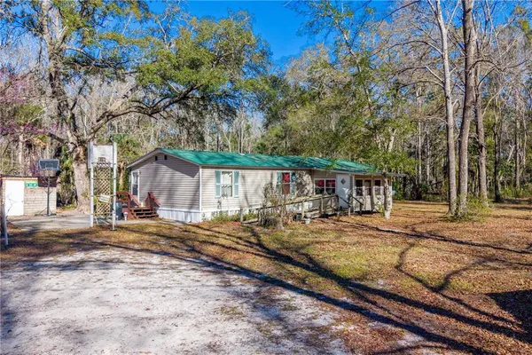 a view of a house with backyard and trees