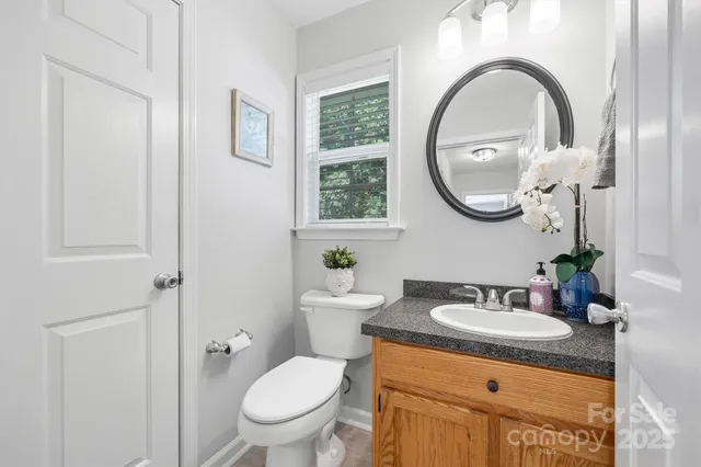 a bathroom with a granite countertop toilet a sink and a mirror