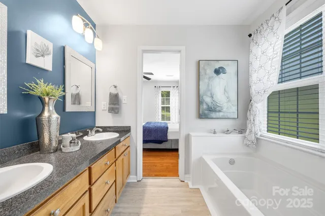 a spacious en suite bathroom with a granite countertop tub sink and mirror
