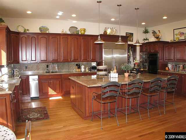 12680 Silver Wolf Road Reno, NV 89511 - Photo 5 of 9 a kitchen with stainless steel appliances kitchen island granite countertop a stove a sink and a microwave