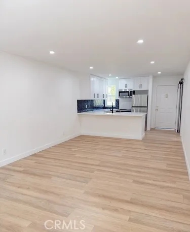 a view of kitchen with kitchen island a sink wooden floor and a refrigerator