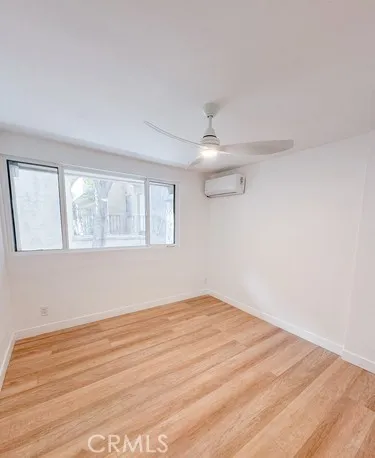 an empty room with wooden floor fan and windows