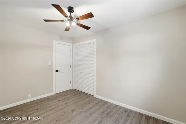 an empty room with wooden floor and ceiling fan