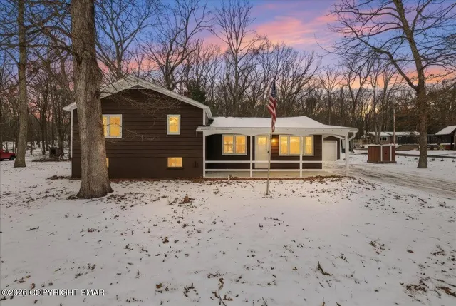 a front view of a house with a yard covered in snow