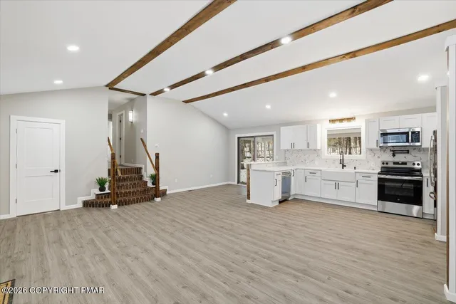 a view of a kitchen with stainless steel appliances wooden floor and living room