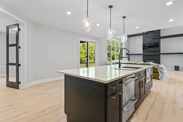 a kitchen with stainless steel appliances granite countertop a sink a stove and a wooden floors