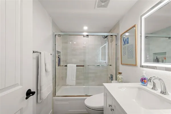 a bathroom with a shower sink vanity mirror and toilet