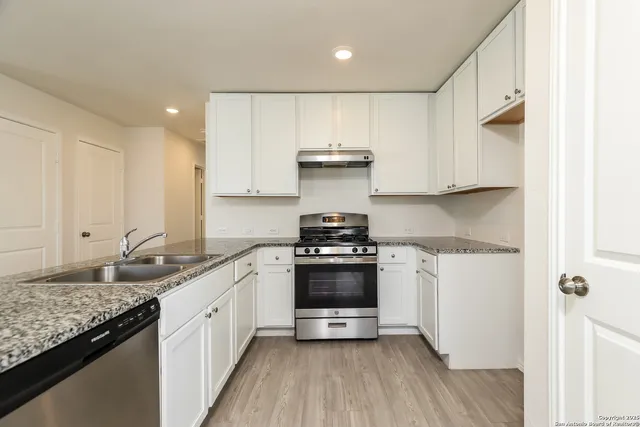 a kitchen with granite countertop cabinets stainless steel appliances and a wooden floor