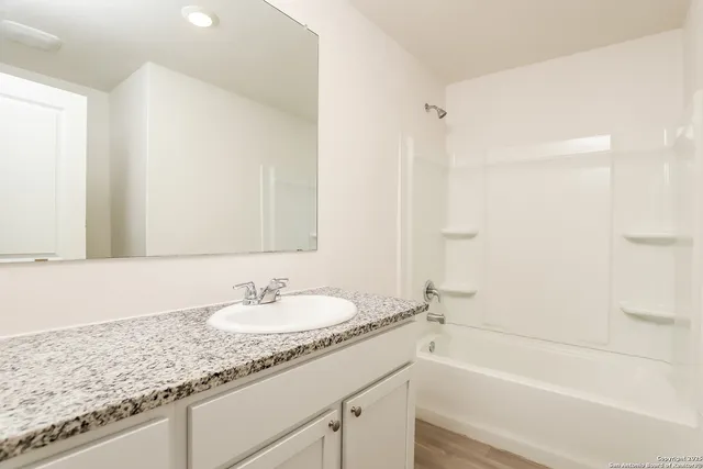 a bathroom with a granite countertop sink a mirror and a bathtub