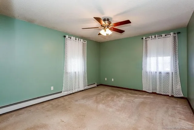 an empty room with windows and fan