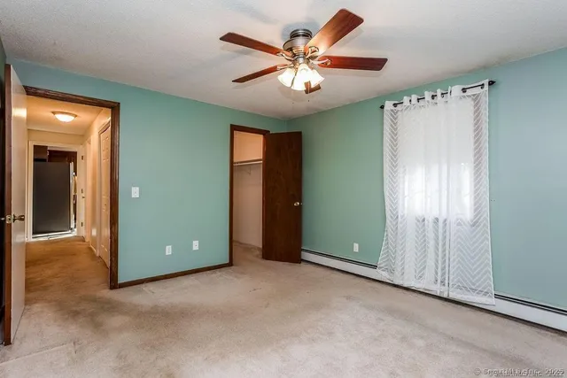 an empty room that has a large mirror and a chandelier fan