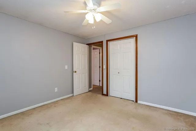 an empty room with a chandelier fan and closet area