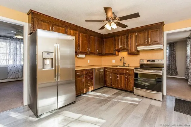 a kitchen with stainless steel appliances granite countertop a refrigerator a sink a stove and a cabinets
