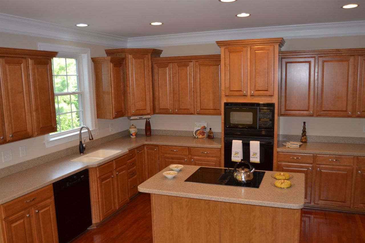 8425 Henderson Road Apex, NC 27539 - Photo 6 of 25 Plenty of cabinets (staggered), solid surface countertops, crown molding, cooking island, canister lights, a large window to over look the backyard with easy access to the screened porch and deck! Large Kitchen