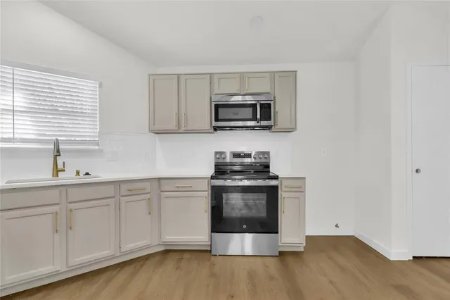 a kitchen with stainless steel appliances a stove microwave and sink
