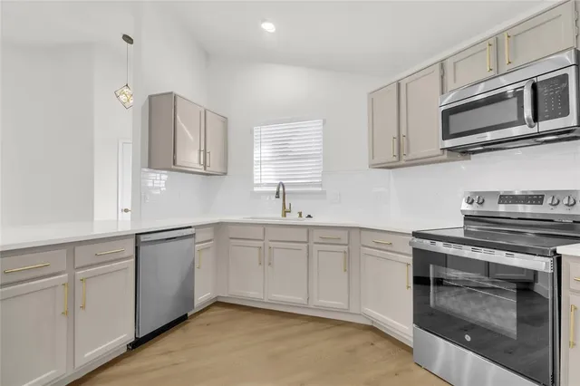 a kitchen with cabinets stainless steel appliances and sink