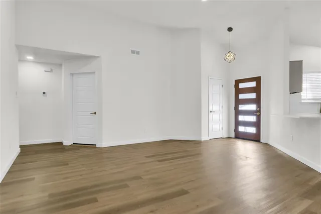 a view of an empty room with window and wooden floor