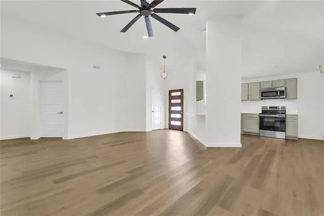 a view of an empty room with window and wooden floor