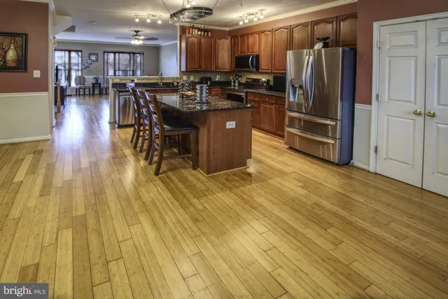a kitchen with stainless steel appliances granite countertop a refrigerator a stove and a wooden floors