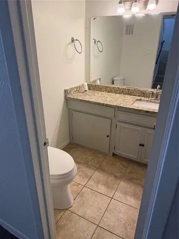 a bathroom with a granite countertop sink toilet and mirror