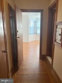 a view of a hallway with wooden floor and a bathroom