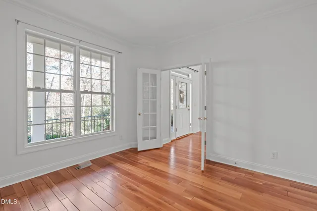 a view of an empty room with wooden floor and a window