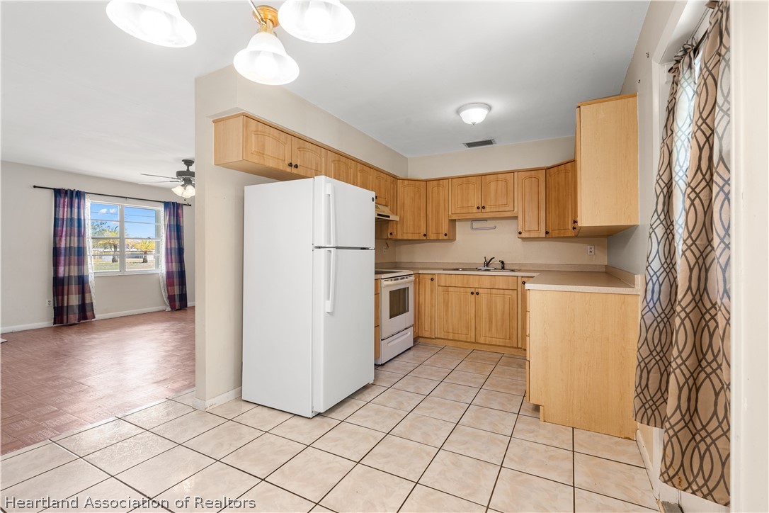 3303 Lakewood Road Sebring, FL 33875 - Photo 23 of 34 a kitchen with a refrigerator a stove top oven and cabinets