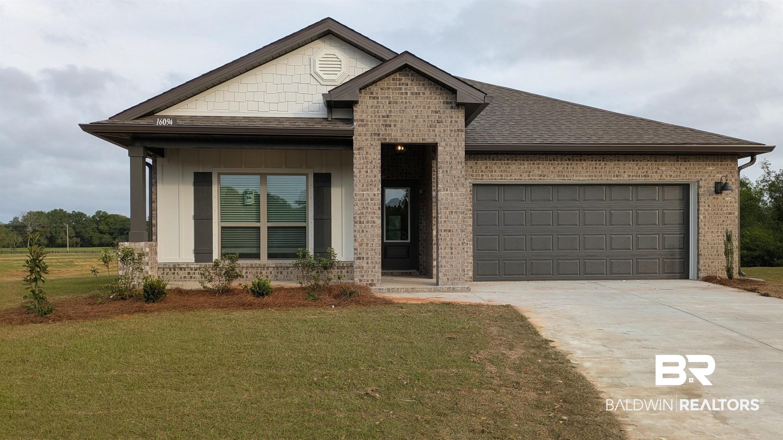 16094 Rhine Road Fairhope, AL 36532 - Photo 1 of 47 View of front of property featuring driveway, an attached garage, a porch, brick siding, and a front lawn