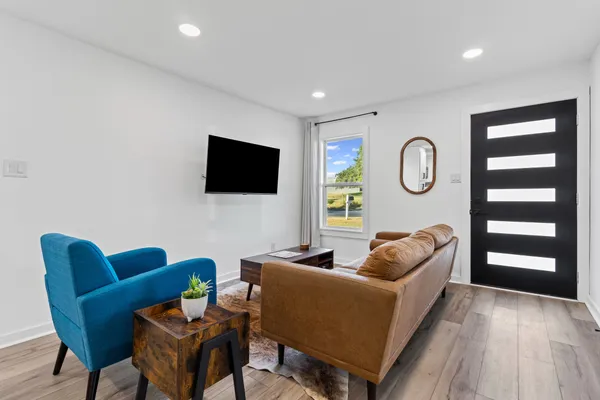 a living room with furniture a flat screen tv and kitchen view