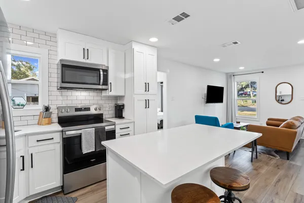 a kitchen with stainless steel appliances kitchen island granite countertop a stove a sink a dining table and chairs