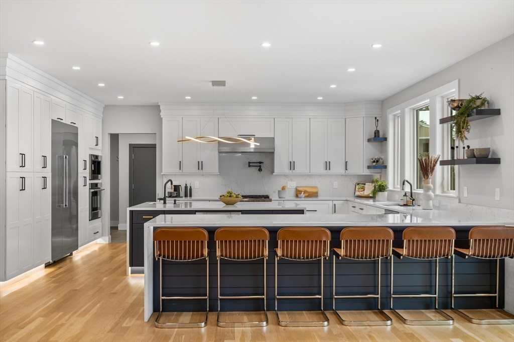 68 Longmeadow Road Belmont, MA 02478 - Photo 2 of 39 a large kitchen with kitchen island granite countertop a dining table chairs and white cabinets