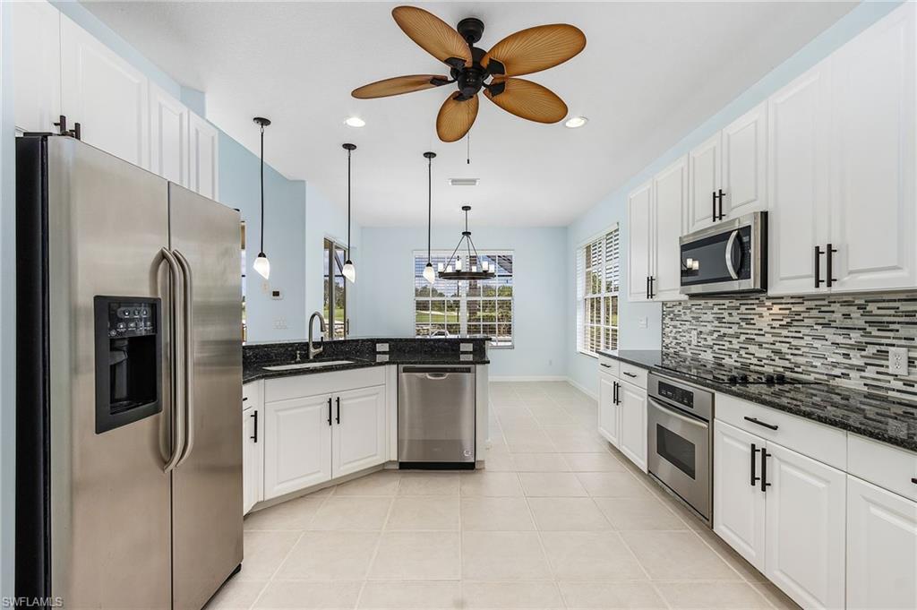 a kitchen with stainless steel appliances granite countertop a stove a refrigerator a sink a stove and white cabinets