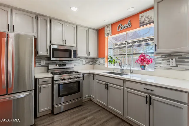 a kitchen with stainless steel appliances a sink cabinets and a window