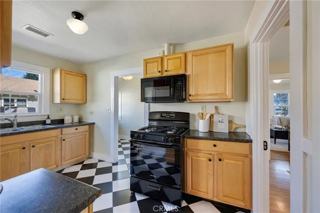 a kitchen with stainless steel appliances granite countertop a stove top oven a sink dishwasher and white cabinets with wooden floor