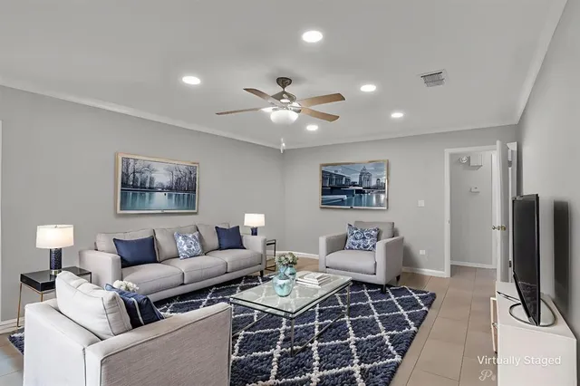 a living room with furniture a flat screen tv and a ceiling fan