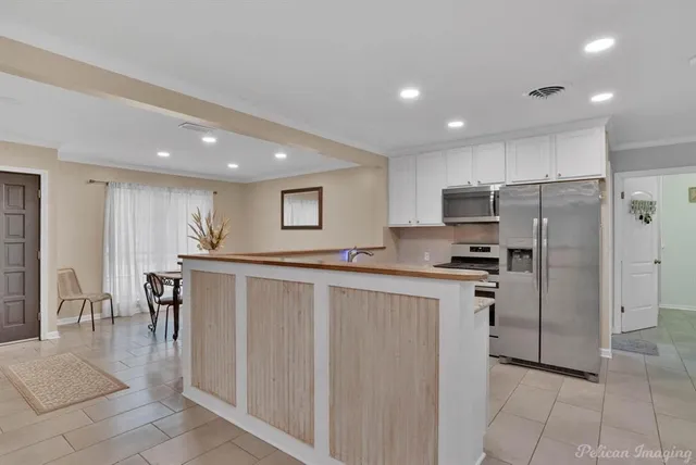 a kitchen with kitchen island a counter top space cabinets and stainless steel appliances