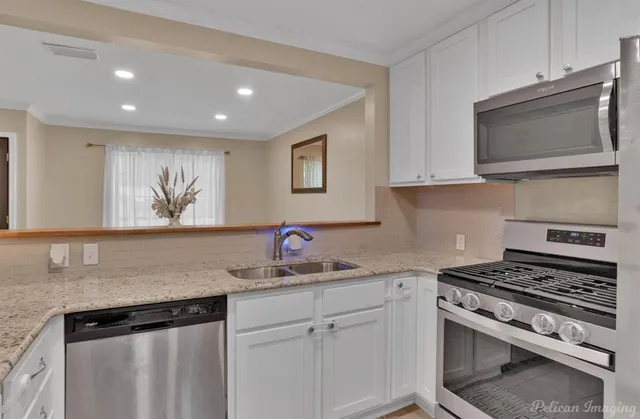 a kitchen with stainless steel appliances granite countertop a sink dishwasher a stove microwave and oven with white cabinets