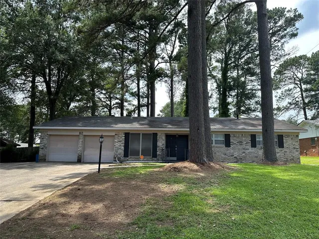a view of a house with a yard and large tree