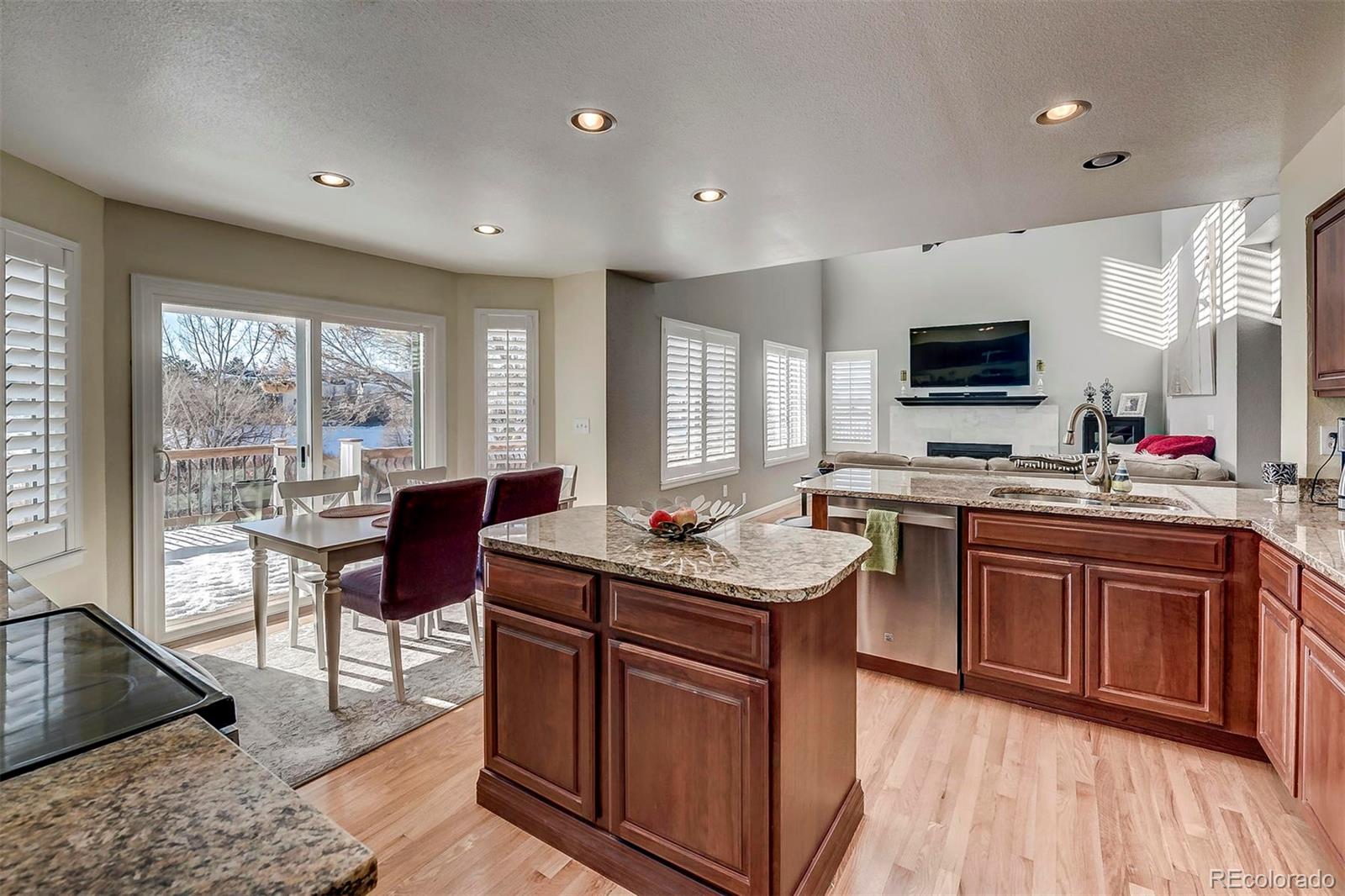 9847 Spring Hill Lane Highlands Ranch, CO 80129 - Photo 12 of 33 a kitchen with stainless steel appliances granite countertop a stove a sink dishwasher a microwave oven with a dining table and chairs