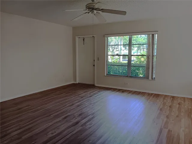 an empty room with wooden floor chandelier and windows