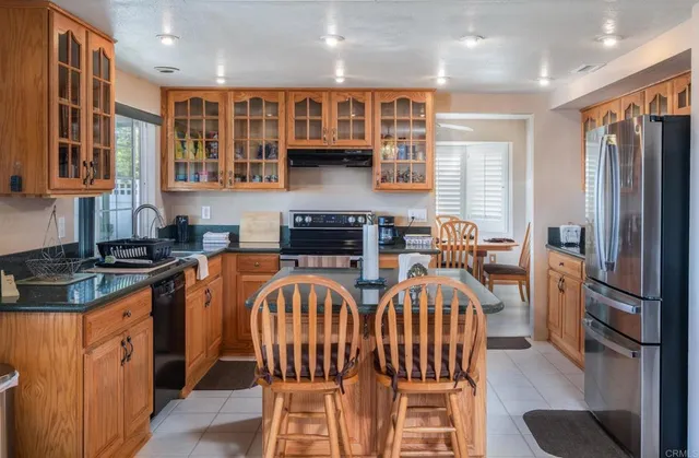 a view of a kitchen with stainless steel appliances granite countertop a stove top oven a sink a dining table and chairs
