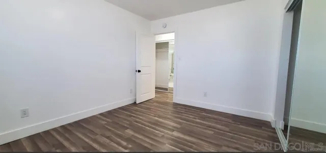a view of an empty room with wooden floor and closet