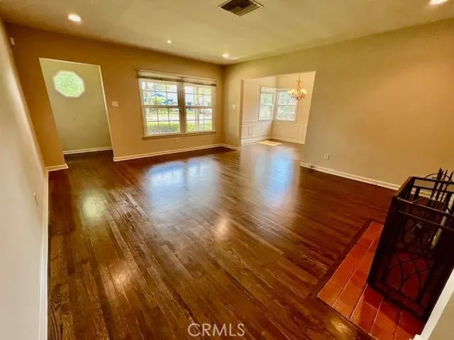a view of an empty room with window and wooden floor