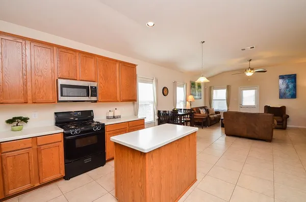 a large kitchen with stainless steel appliances granite countertop a stove a sink dishwasher and a microwave oven with large cabinets