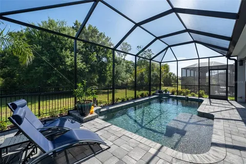 a view of an empty room with wooden floor and a kitchen