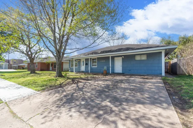 a view of a house with a yard and large tree