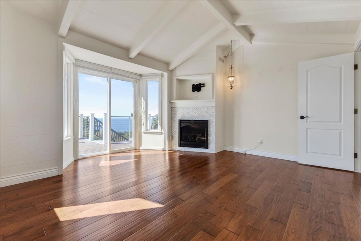 15 Mentone Road Carmel, CA 93923 - Photo 26 of 47 an empty room with wooden floor fireplace and windows